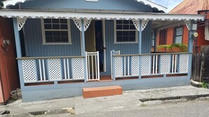 A blue house with a porch, a door, and a small step leading to the entrance.