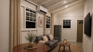 A living room with a sofa, a dining table, a TV, and a refrigerator.