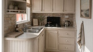 A kitchen with white cabinetry, a gas stove, a sink, and a window with a view.