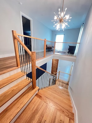 A multi-level wooden staircase with a modern chandelier. - Your cozy Texas home in Fort Worth! 5 min to Downtown FW (Fort Worth)