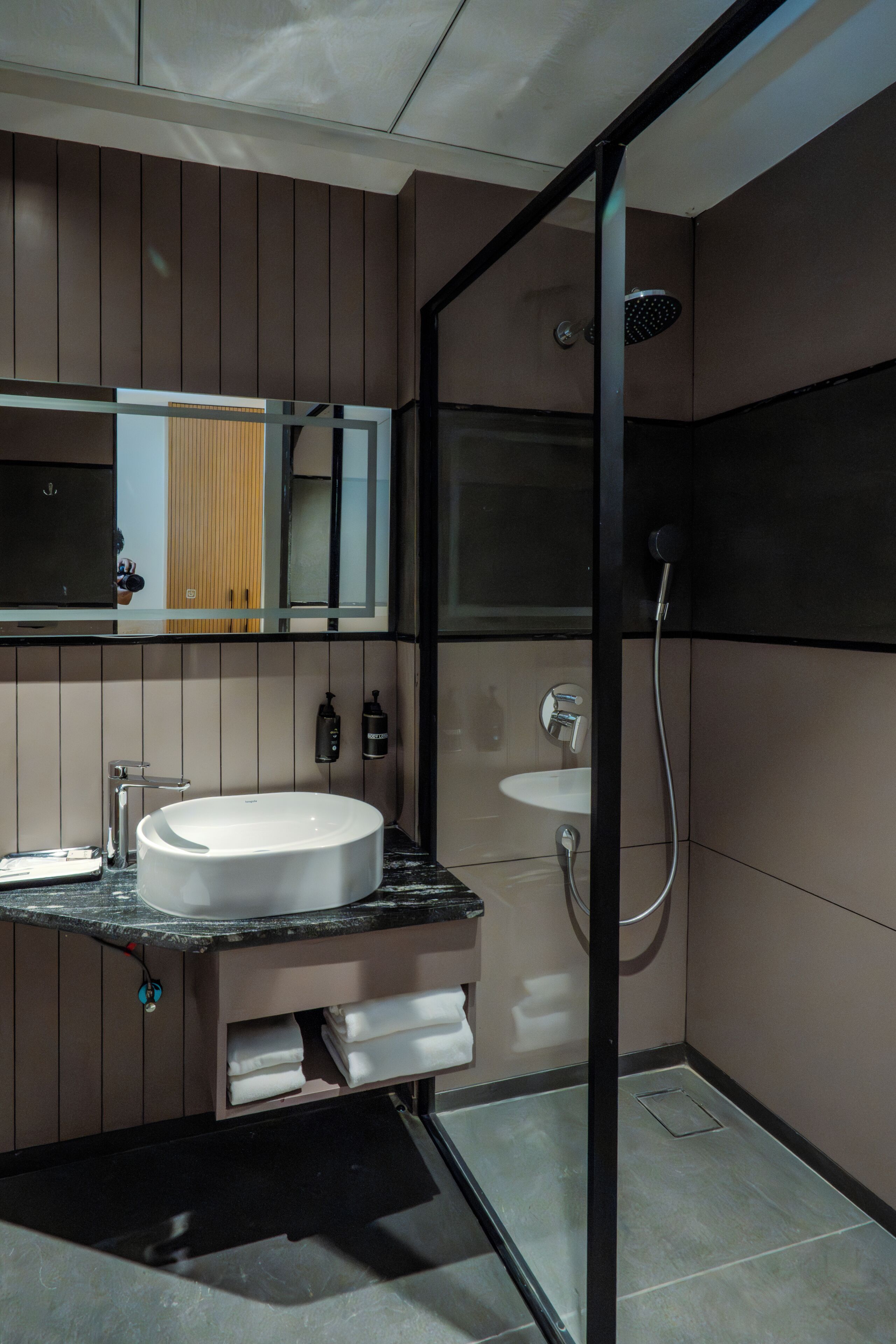 A modern bathroom with a large mirror, a sink, a shower, and a toilet.