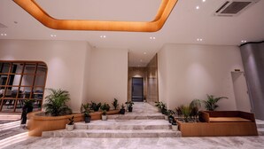 Un intérieur moderne avec un plafond en bois aux lignes courbes, des marches en marbre et des plantes en pot.