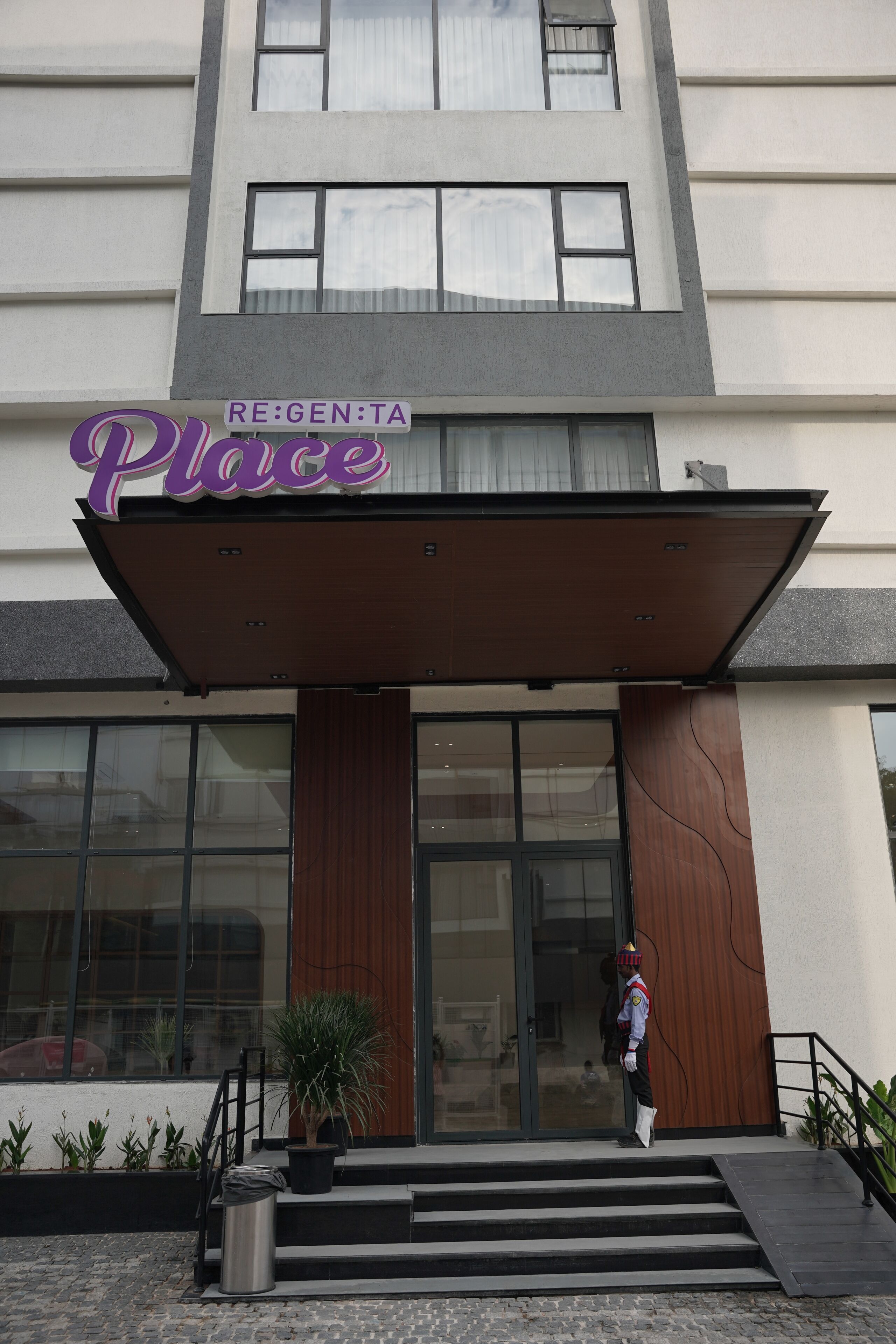 A building with a sign reading 'RE:GEN:TA Place' and a person in uniform standing at the entrance.