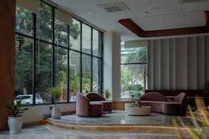 A modern lobby with large windows, a curved seating area, and a central coffee table. - Regenta Place Hitech City, Hyderabad – A Royal Orchid Hotels Brand (Hyderabad)