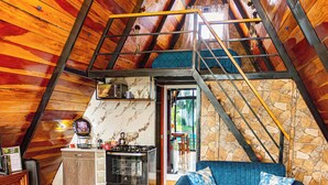 A loft-style room with a kitchen, a blue sofa, and a chandelier.