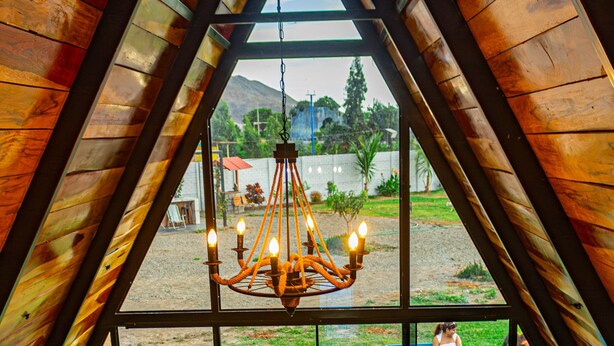 A room with a large window, a chandelier, a wooden bench, and a table.