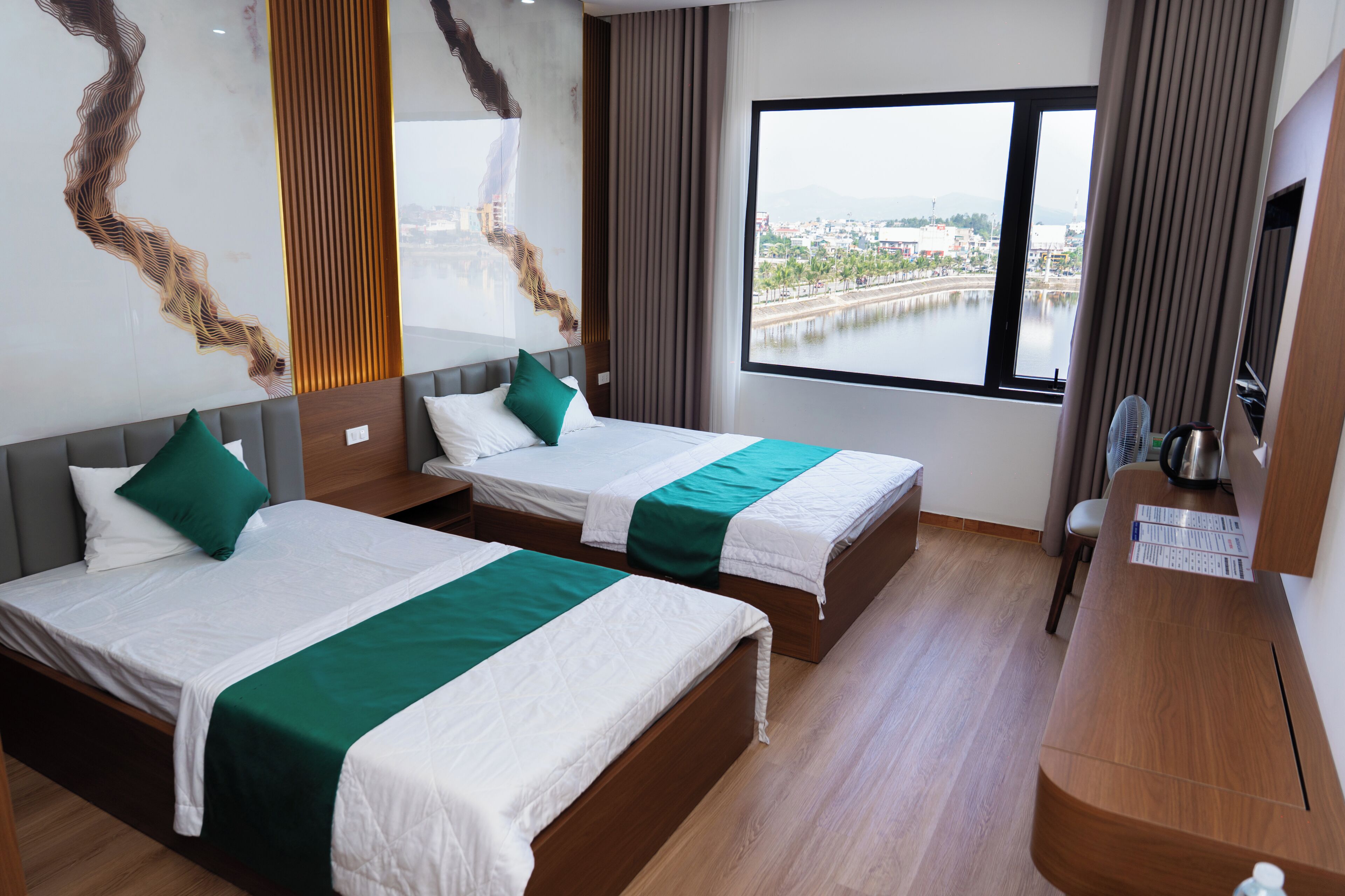Ein Hotelzimmer mit zwei Betten, einem großen Fenster und Blick auf ein Gewässer.