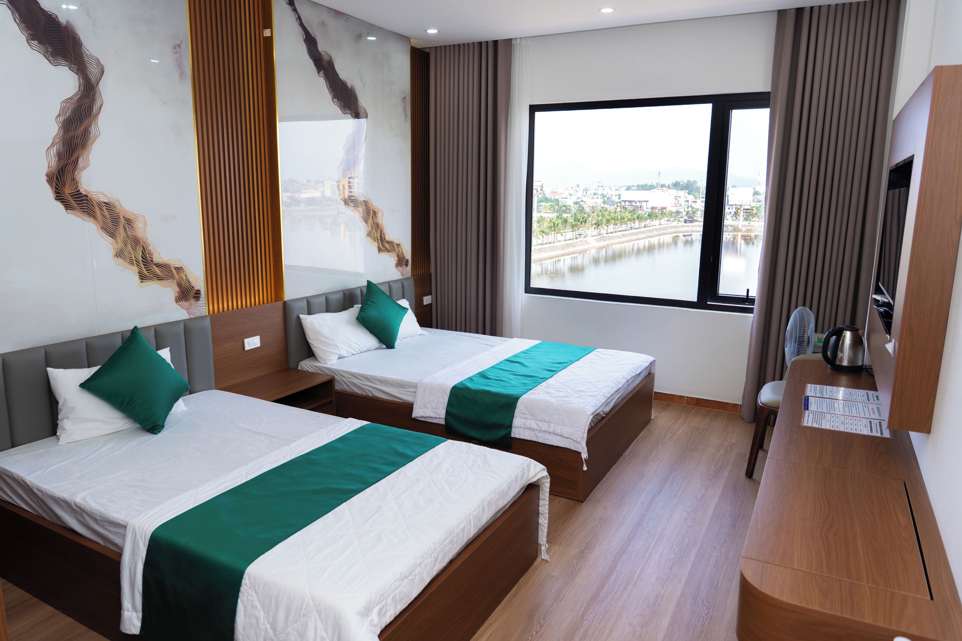 A hotel room with two beds, a large window, and a view of a body of water.