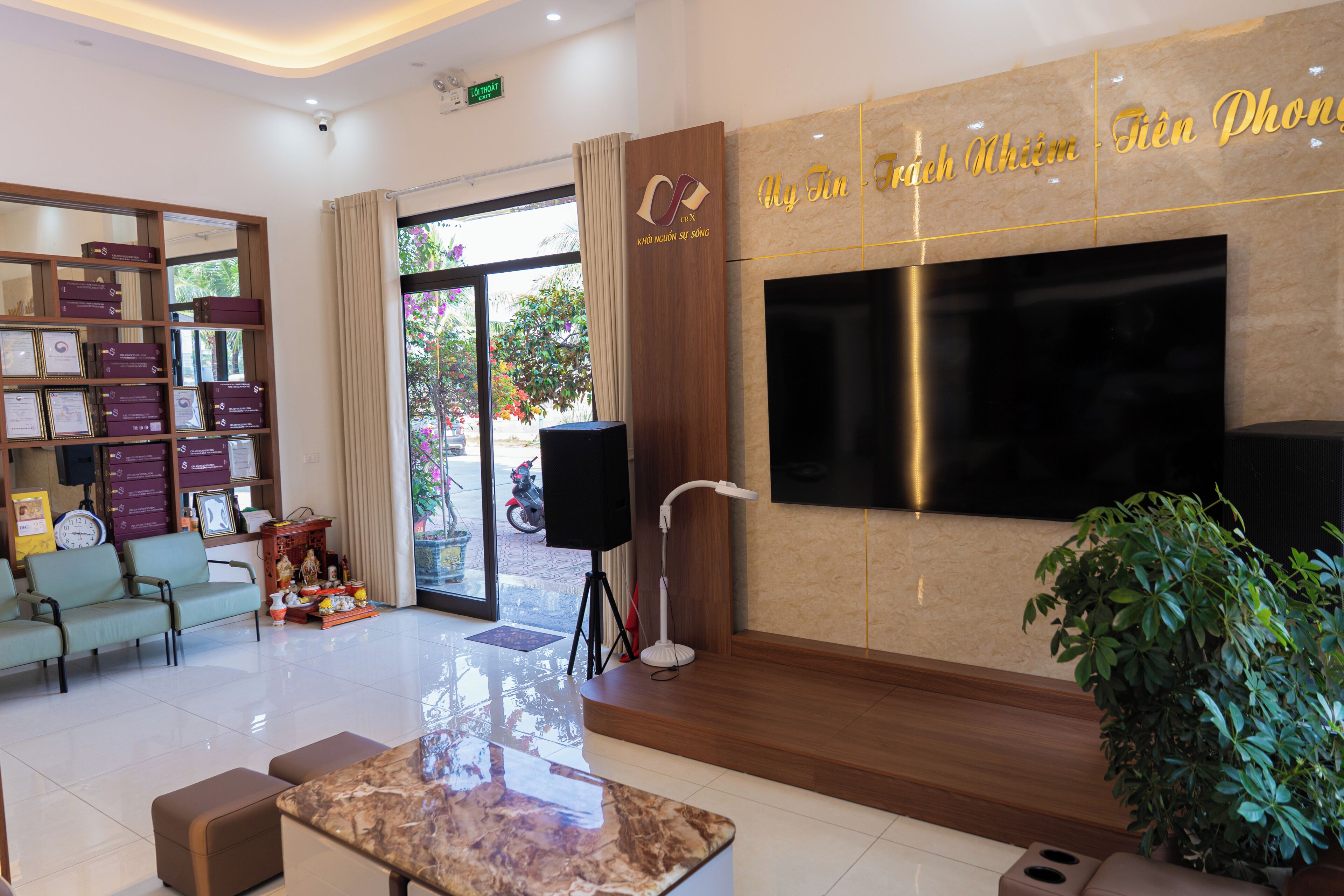A hotel lobby with a reception desk, seating area, and a large flat-screen TV mounted on the wall.