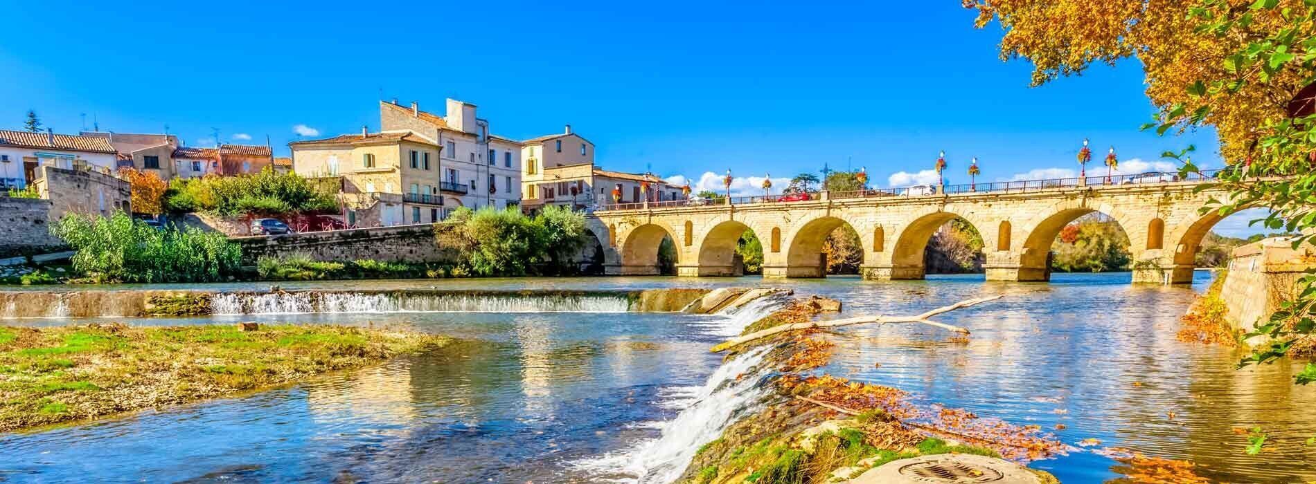Un pont de pierre enjambe une rivière, avec des bâtiments sur la rive opposée.