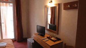 A hotel room with a bed, a desk with a television, a mirror, and a small window. - Ducata Hotel - Single Room With Balcony Views (Veroia)