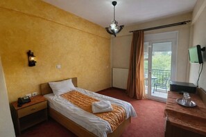 A hotel room with a bed, a nightstand, a desk with a chair, a television, and a balcony with a view.