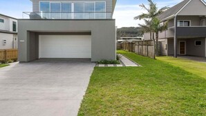 A modern two-story house with a garage, a covered driveway, and a well-maintained lawn. - Aiturangi Retreat Whangamata (Whangamata)
