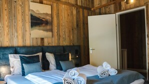 Una stanza con rivestimenti in legno, un letto, cuscini e un quadro appeso al muro.