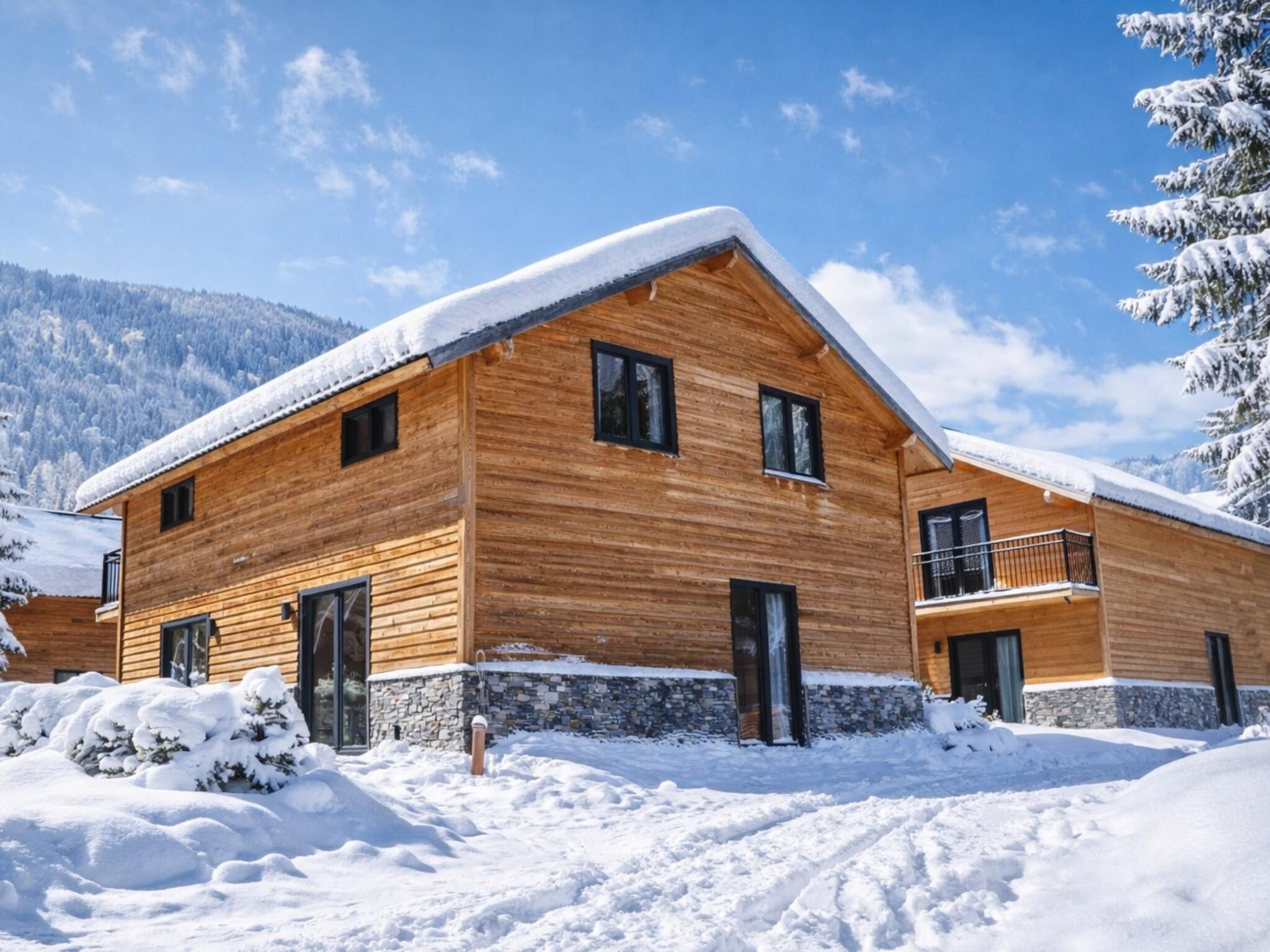 A wooden cabin with a stone foundation, multiple windows, and a balcony.