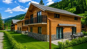 Una baita di legno con balcone, fondamenta in pietra e vista sulla foresta circostante.