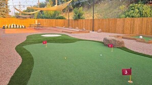 A miniature golf course with three holes, a wooden fence, and a natural backdrop. - Bright Studio in Manitou Springs, Walk Downtown (Manitou Springs)