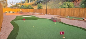 A miniature golf course with three holes, a wooden fence, and a natural backdrop. - Bright Studio in Manitou Springs, Walk Downtown (Manitou Springs)
