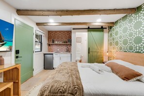 Un dormitorio con cama, escritorio, kitchenette pequeño y baño.