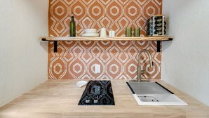 A kitchen with a patterned backsplash, a wooden countertop, a sink, and a stove. - Bright Studio in Manitou Springs, Walk Downtown (Manitou Springs)
