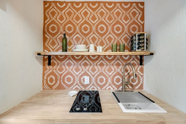 Een keuken met een decoratieve spatwand, een houten aanrecht, een spoelbak en een fornuis.