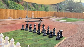 Un jeu d’échecs installé sur une pelouse, avec une table de pique-nique à proximité.