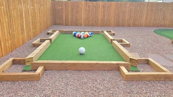 Une table de billard avec une bille au centre, entourée de cadres en bois et d’une pile de billes de billard.
