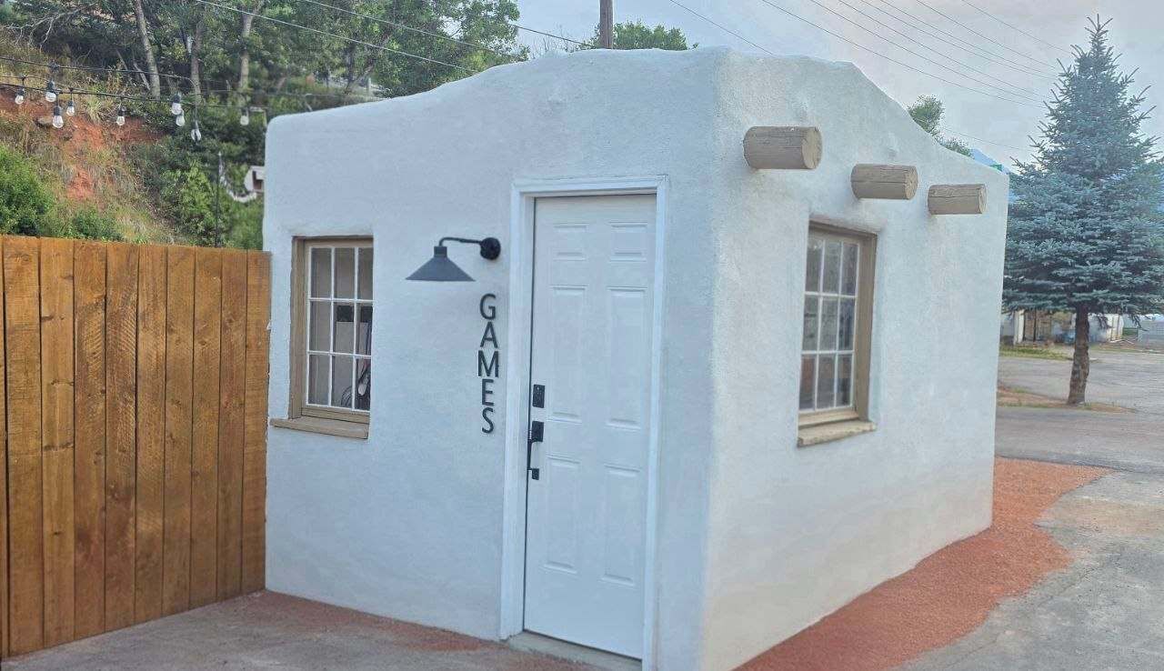A small, single-story building with a white exterior, a door, and two windows.