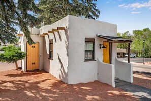 A white building with a wooden door, a window, and a small porch. - Modern Studio in Manitou Springs, Walk Downtown (Manitou Springs)