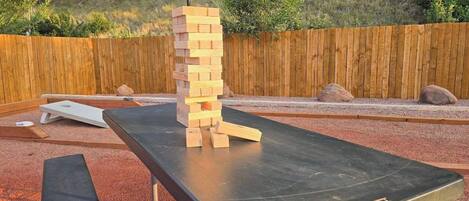 Una estructura de madera que recuerda a una torre de Jenga sobre una mesa negra al aire libre.