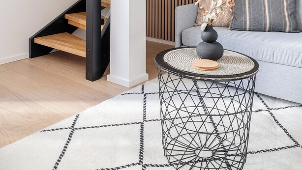 Un interior moderno con una escalera, un sofá y una mesa de centro redonda.