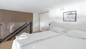 Un dormitorio moderno con una cama, un cuadro colgado en la pared y un muro de listones de madera.