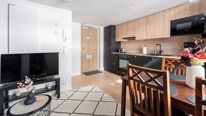 Una cocina moderna con microondas negro, armarios de madera y un comedor con mesa y sillas.