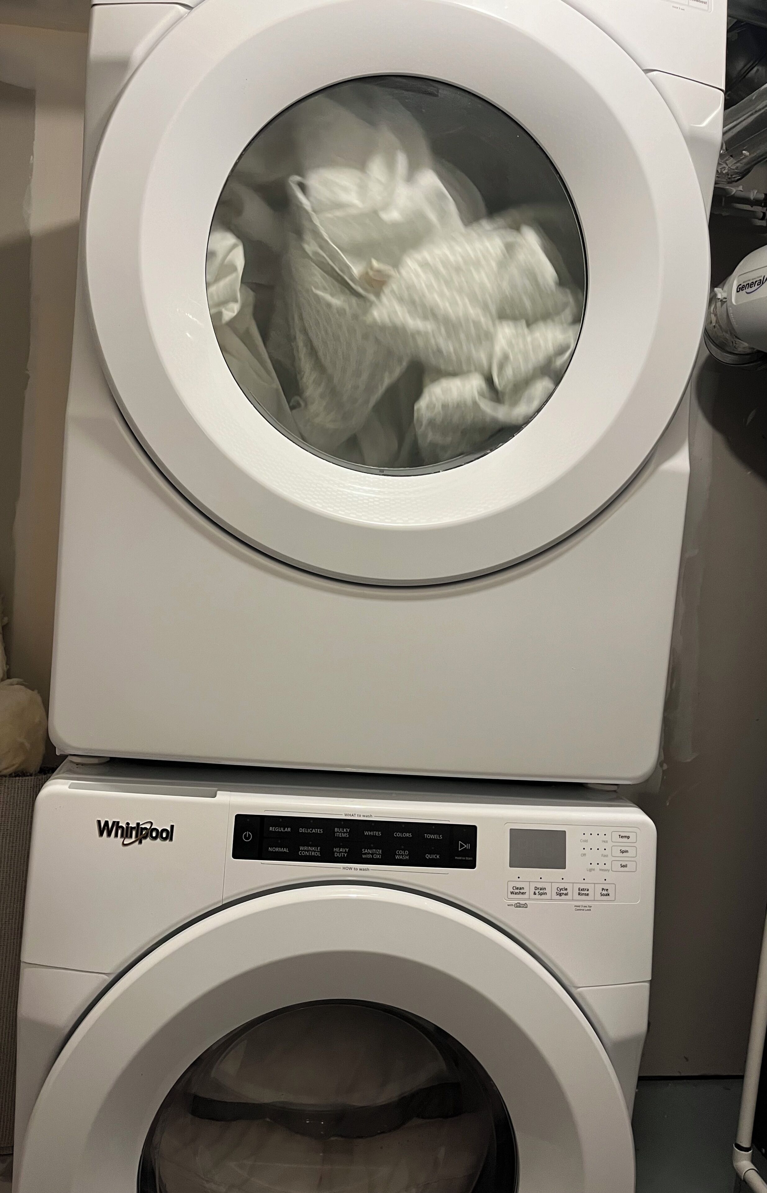 A stacked washer and dryer unit with a control panel and a glass door.