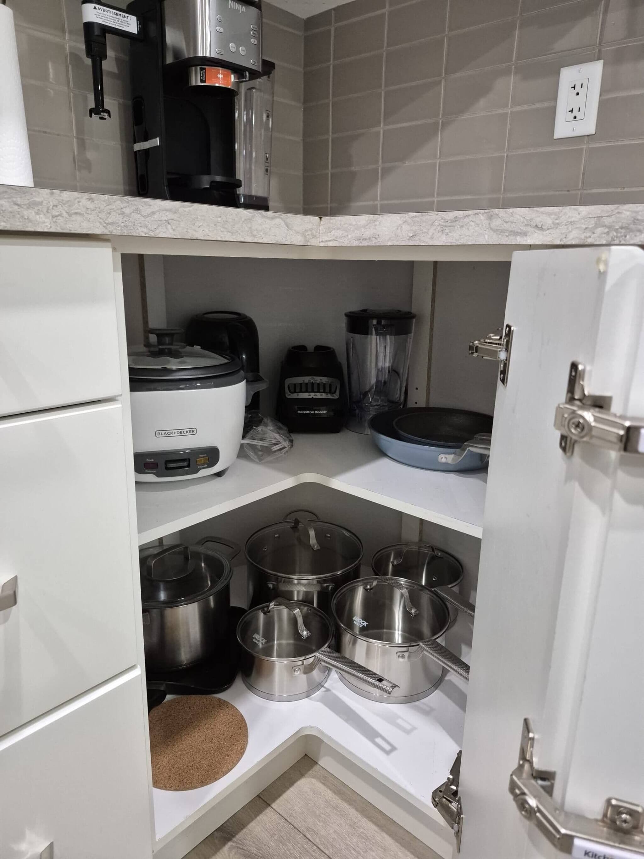 A kitchen with a coffee maker, blender, and various pots and pans.