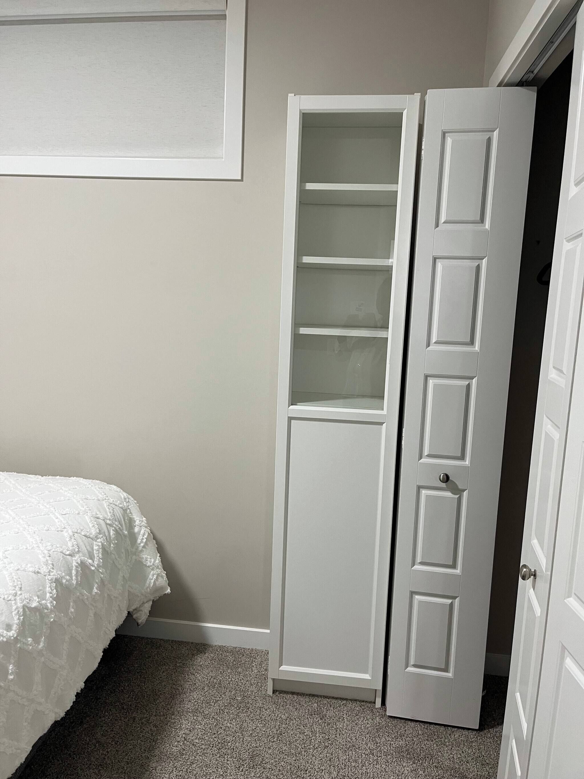 Une chambre à coucher avec un lit, une porte blanche et une armoire avec un miroir.