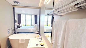 A modern bathroom with a freestanding bathtub, a sink with a mirror, and a towel rack. - Forest Sky Villa - Flamingo Cat Ba (Hai Phong)