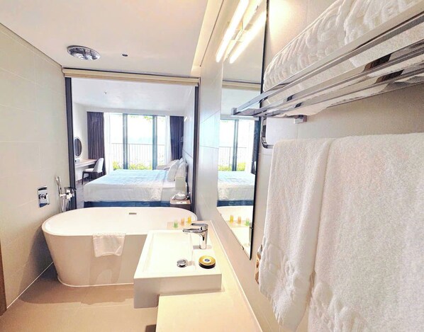 Une salle de bain moderne avec une baignoire sur pieds, un lavabo avec un miroir et un porte-serviettes.