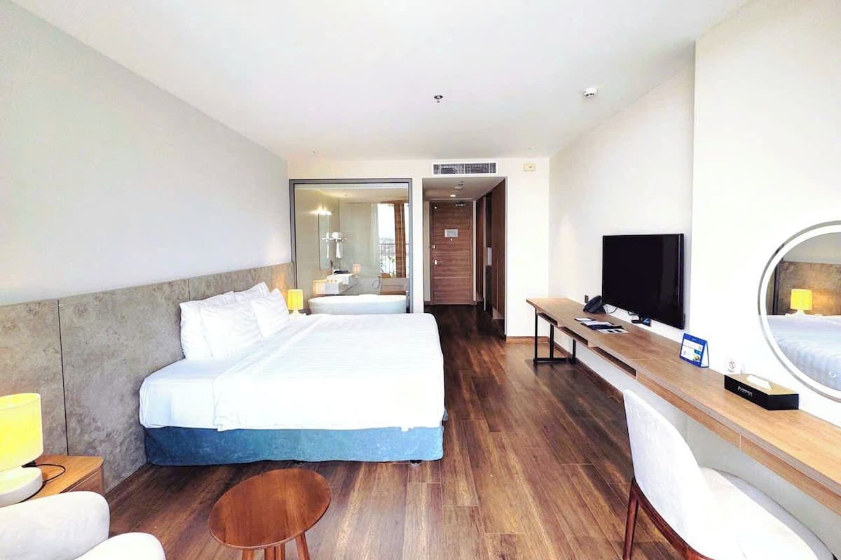 A hotel room with two beds, a desk, a chair, a TV, and a mirror.