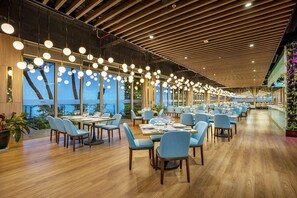 A spacious restaurant with long tables, blue chairs, and hanging spherical lights. - Forest Sky Villa - Flamingo Cat Ba (Cat Hai)