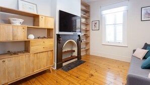 Una sala de estar moderna con estantes de madera, una chimenea, un televisor de pantalla plana y una ventana con persianas.
