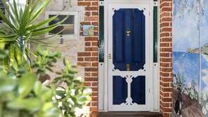Una puerta azul con manija de bronce, un marco blanco y un muro de ladrillo.