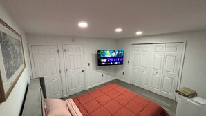 A bedroom with a bed, a television mounted on the wall, and white doors. - 4 Beds • Parking • Netflix • W/D • Fast Wifi (Wilkes-Barre)