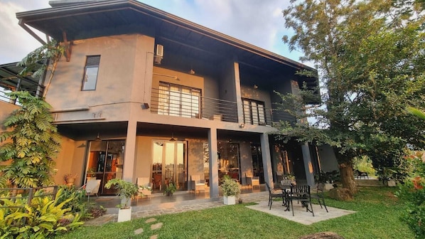 A two-story house with a balcony, large windows, and a garden area.