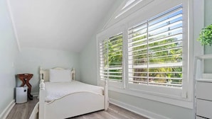 Un dormitorio con cama, ventana con persianas, radiador y cómoda.