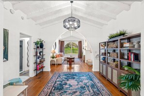Ein geräumiges Wohnzimmer mit hoher Decke, Holzboden, einer zentralen Sitzecke und einem großen Bücherregal.