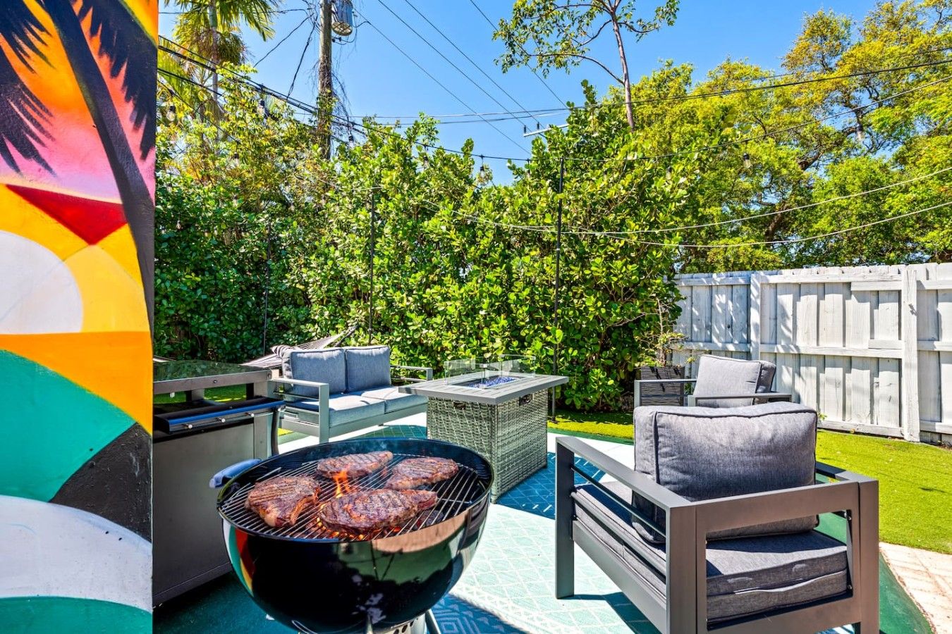 Un patio trasero con una parrilla, mobiliario exterior y una piscina.