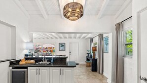 Een keuken met witte kasten, een zwart aanrecht en een hangende lamp.
