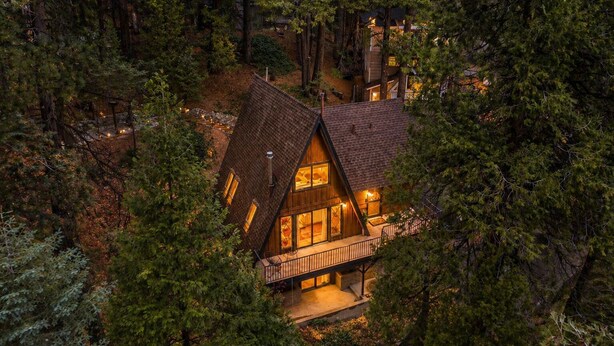 Eine Hütte mit einem steilen Satteldach, großen Fenstern und einem Balkon.