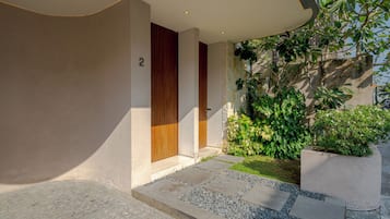 A modern building entrance with a stone pathway, a wooden door, and a number '2' on the wall.